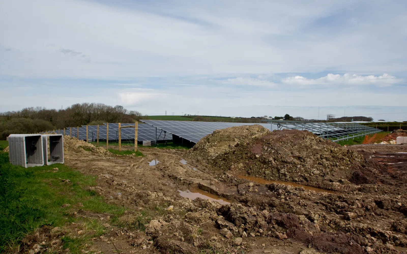 A solar farm under construction seen from the air, rows of mounting structures going in across cleared ground